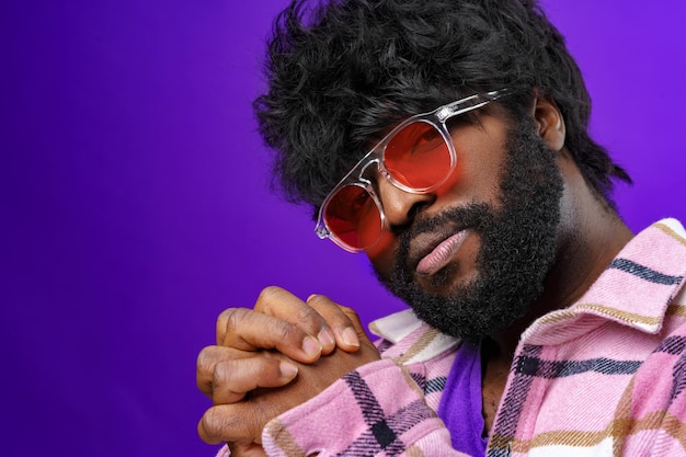 Ritratto di moda di un uomo afroamericano con occhiali su sfondo viola