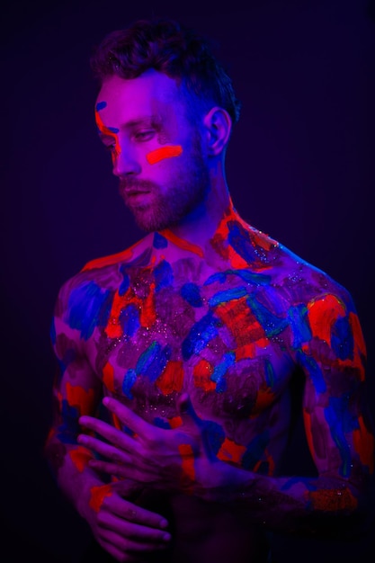 Ritratto di moda di un uomo con vernice ultravioletta sul corpo e luce al neon in stile cyberpunk