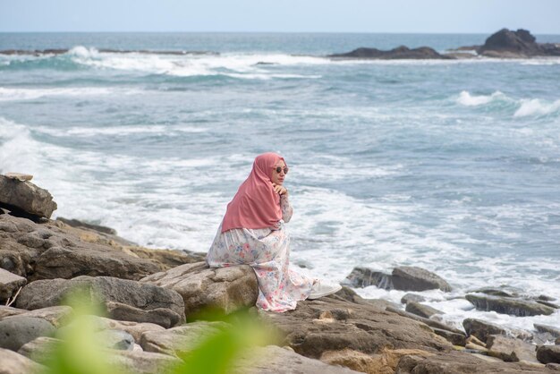 Ritratto di modello asiatico Hijab seduto a Beach Rock