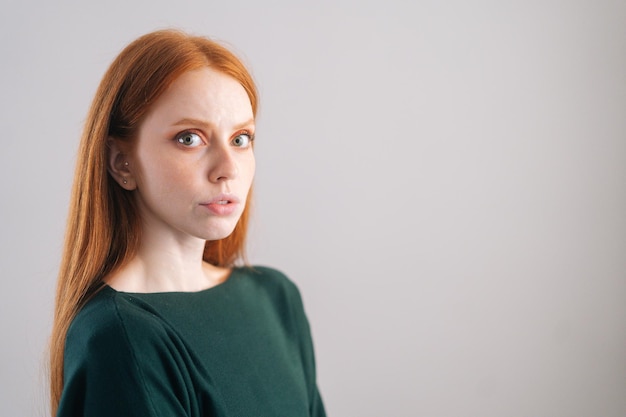 Ritratto di modello di giovane donna rossa seria guardando la fotocamera su sfondo bianco Colpo medio di signora dai capelli rossi sicura con bellezza naturale in posa in studio professionale