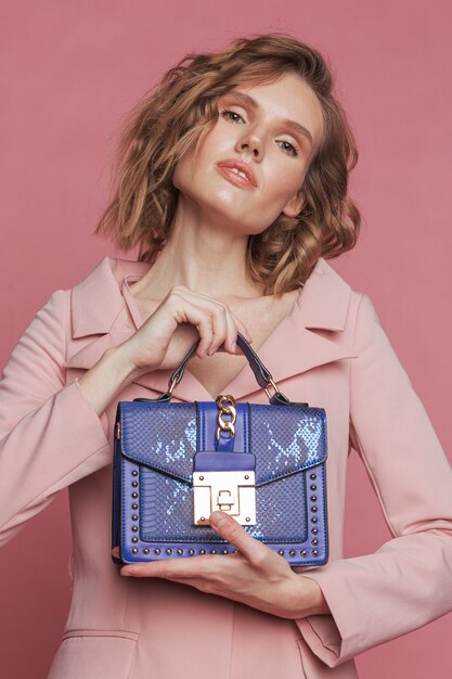 Ritratto di modello in rosa che tiene la borsa blu.