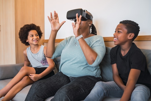 Ritratto di nonna afroamericana e nipoti che giocano insieme con gli occhiali Vr a casa.