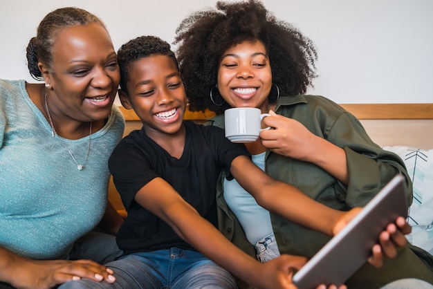 Ritratto di nonna afroamericana, madre e figlio che prendono un selfie con tavoletta digitale a casa. Concetto di tecnologia e stile di vita.