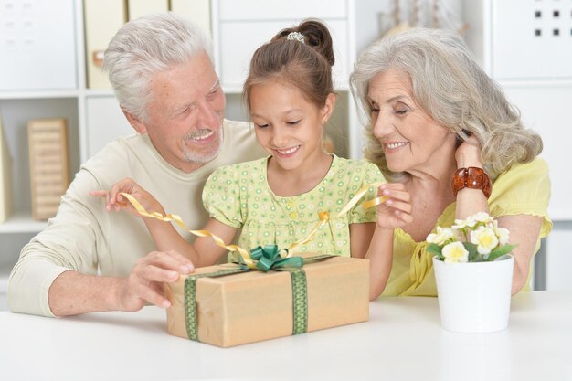 Ritratto di nonni e nipote con grande confezione regalo a casa