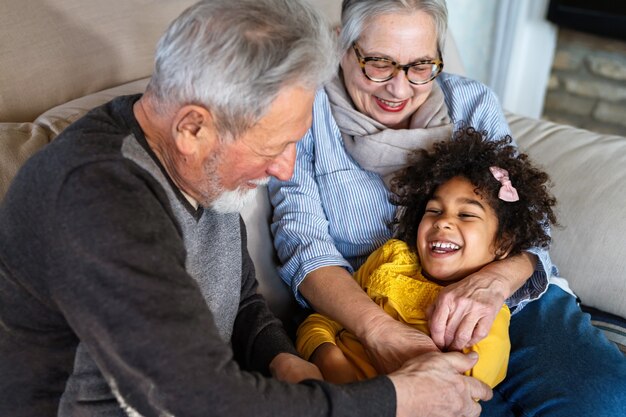 Ritratto di nonni felici con bambino che gioca insieme a casa. Concetto di solidarietà familiare amore