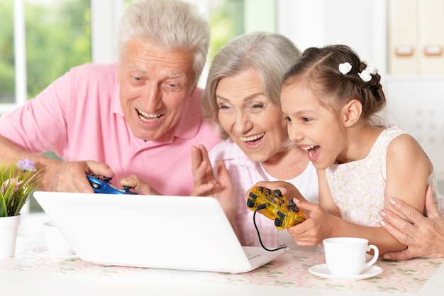 Ritratto di nonni felici e di una bambina che usa il laptop