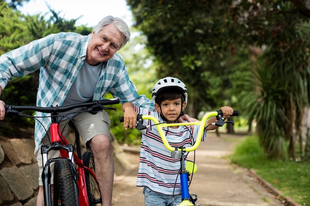 Ritratto di nonno e nipote in piedi con la bicicletta nel parco