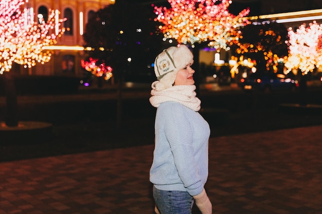 Ritratto di notte d'inverno di una bella donna in abiti invernali. cappello di pelliccia e guanti.