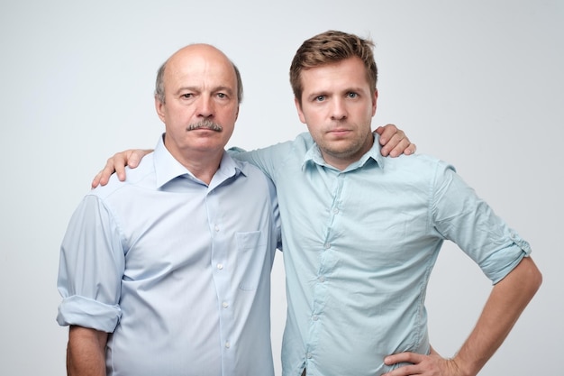 Ritratto di padre e figlio maturi in piedi con un'espressione seria sul viso Buone relazioni in famiglia