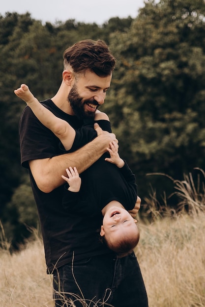 Ritratto di padre e figlio Un padre alla moda con la barba tiene in braccio un bambino