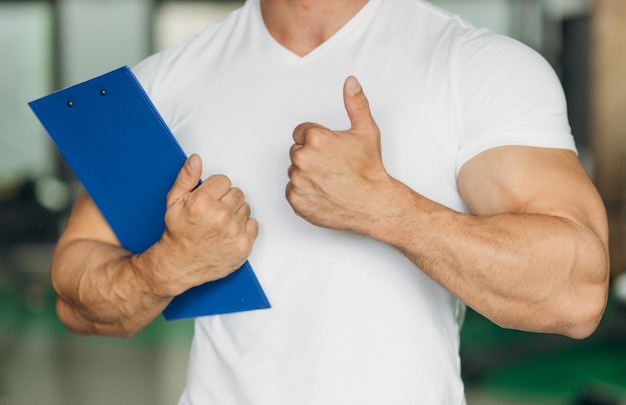 Ritratto di personal trainer che tiene appunti con piano di allenamento in palestra