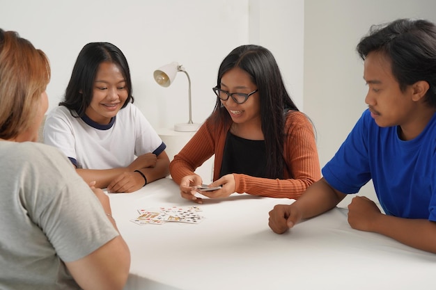 Ritratto di persone asiatiche che giocano a carte a casa, ridendo allegramente. Avvicinamento.