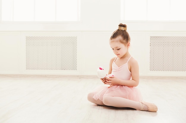 Ritratto di piccola ballerina sul pavimento, copia dello spazio. Bambina sorridente che sogna di diventare ballerina professionista, scuola di danza classica