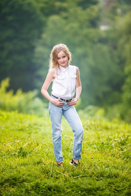 Ritratto di piccola bella ragazza bambino alla moda su sfondo verde foresta