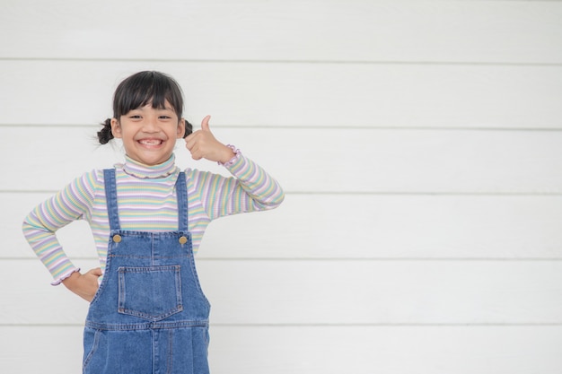 Ritratto di piccola ragazza asiatica carina con il suo tonfo, concetto pubblicitario, piccolo adolescente asiatico batte con lo sfondo bianco e lo spazio