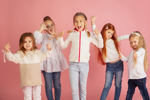 Ritratto di piccoli bambini caucasici con emozioni luminose isolate su sfondo rosa studio