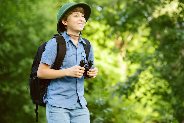 Ritratto di piccolo esploratore con binocolo nella foresta