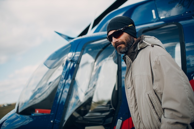 Ritratto di pilota di elicottero in piedi vicino al veicolo nell'aeroporto di campo.