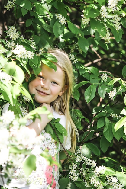 Ritratto di primavera di bambina con fiori in una giornata di sole