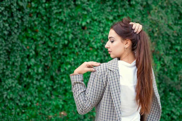 Ritratto di profilo di una bella ragazza del Medio Oriente sullo sfondo di un muro verde di piante