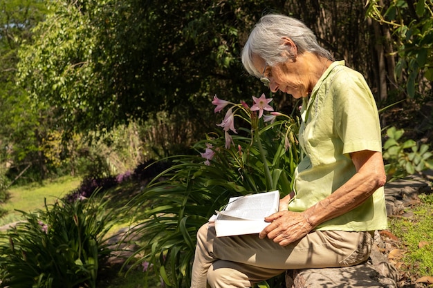 Ritratto di profilo di una donna anziana che legge un libro in un giardino