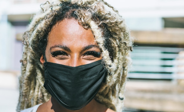 Ritratto di ragazza africana con i dreadlocks biondi che indossa una maschera protettiva per la prevenzione del Coronavirus