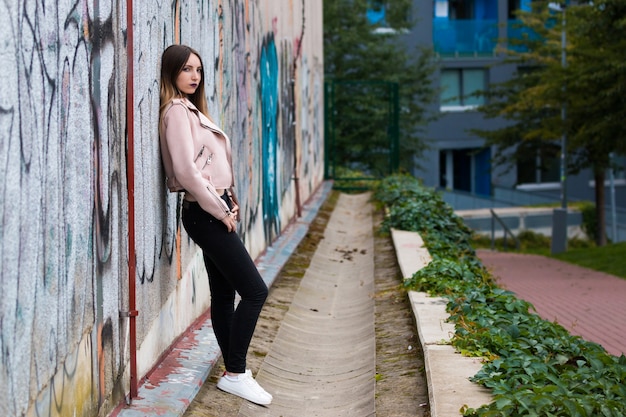 Ritratto di ragazza alla moda sul muro di graffiti