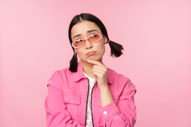 Ritratto di ragazza asiatica triste e cupa imbronciata dalla delusione in piedi sconvolto su sfondo rosa studio Copia spazio
