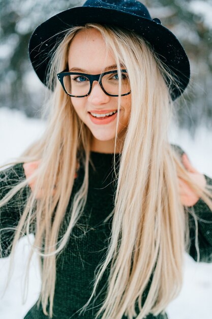 Ritratto di ragazza bionda abbastanza elegante in cappello e occhiali