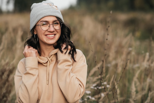 ritratto di ragazza bruna sorridente con gli occhiali nel campo