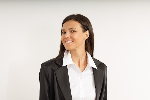 Ritratto di ragazza bruna sorridente felice vestita con camicia bianca e giacca nera Bellissimo modello su sfondo bianco isolato Studio shot di giovane donna attraente in tailleur