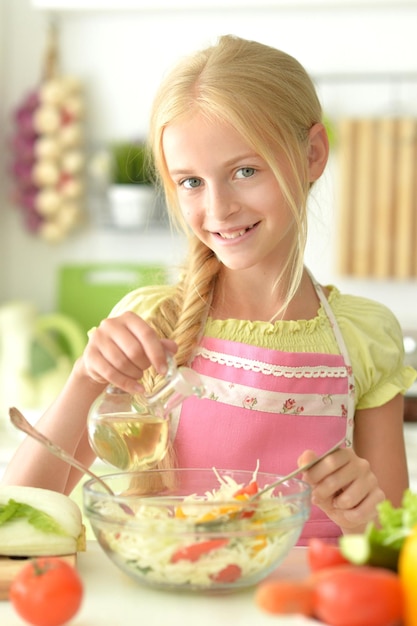 Ritratto di ragazza carina che cucina insalata in cucina