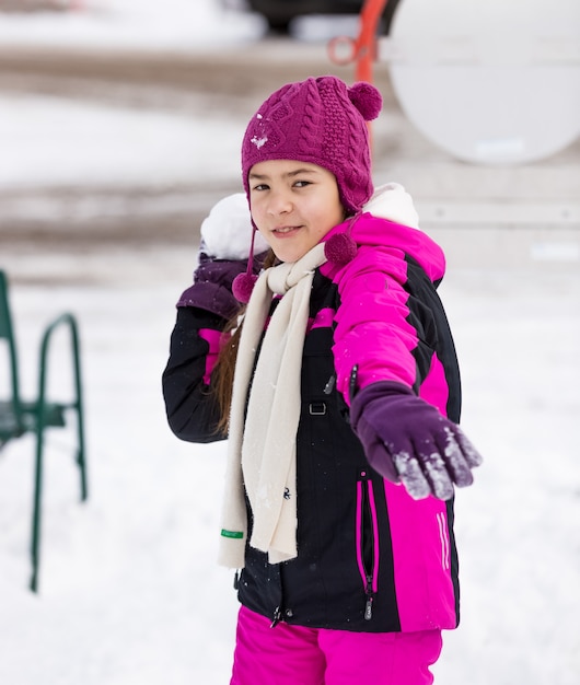 Ritratto di ragazza carina che lancia palle di neve