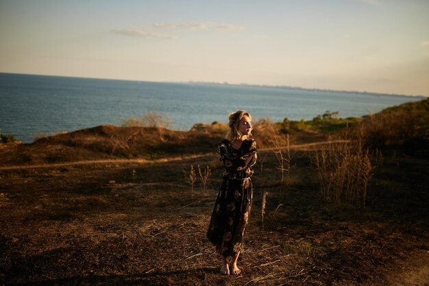 Ritratto di ragazza carina in natura Una ragazza cammina attraverso il campo sullo sfondo del mare