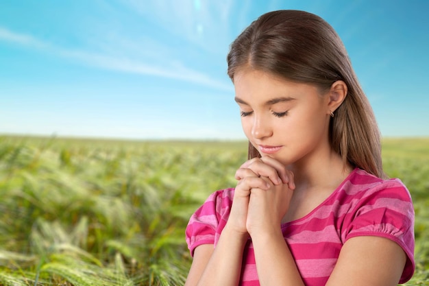 Ritratto di ragazza carina pregare su sfondo verde prato