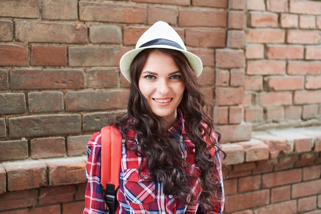 Ritratto di ragazza con cappello sullo sfondo del muro di un edificio in mattoni rossi