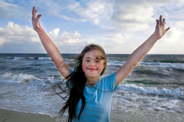 Ritratto di ragazza con sindrome di down sorridente sullo sfondo del mare