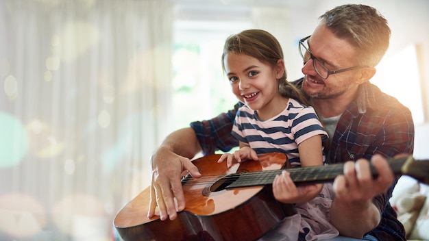 Ritratto di ragazza di lezione di chitarra e padre musicista a casa pronto per l'insegnamento e lo sviluppo della musica Casa della conoscenza musicale e bambino che studia le note dello strumento con felicità e un sorriso da parte del genitore
