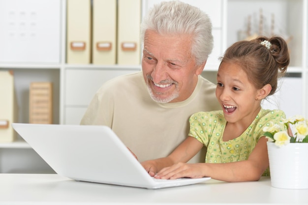 Ritratto di ragazza e nonno con un laptop a casa