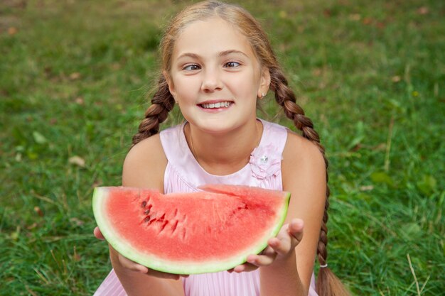 Ritratto di ragazza felice con anguria che si gode il giorno estivo all'aperto