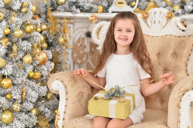 Ritratto di ragazza felice seduta vicino all'albero di Natale