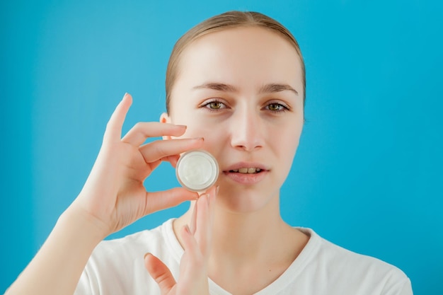 Ritratto di ragazza gioiosa che copre l'occhio con una lattina di crema Sta guardando la fotocamera e ridendo