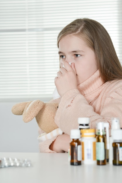 Ritratto di ragazza malata carina che prende medicine a casa