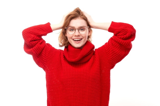 Ritratto di ragazza rossa positiva in maglione rosso di Natale si rallegra emotivamente e si sente felice isolato su sfondo bianco banner pubblicitario