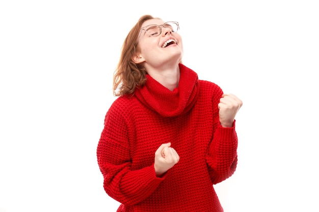 Ritratto di ragazza rossa positiva in maglione rosso di Natale si rallegra emotivamente e si sente felice isolato su sfondo bianco banner pubblicitario