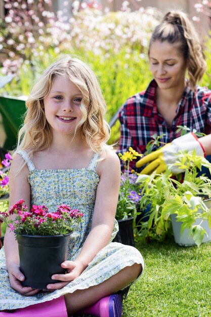 Ritratto di ragazza seduta in giardino con vaso di fiori