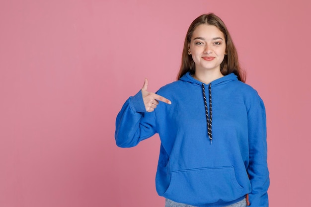 Ritratto di ragazza sicura di capelli biondi che punta con il dito su se stessa mentre sorride alla telecamera