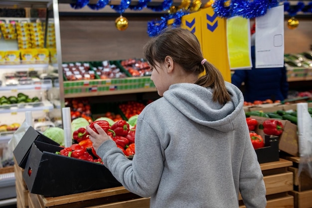 Ritratto di ragazza teenager carina sorridente nel reparto frutta e verdura del supermercato