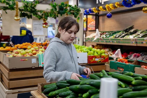 Ritratto di ragazza teenager carina sorridente nel reparto frutta e verdura del supermercato