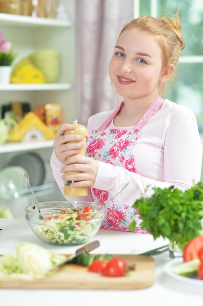 Ritratto di ragazza teenager sveglia che prepara insalata fresca